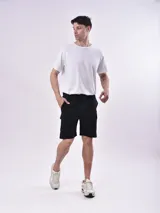 Bermuda cargo color negro con bolsillos laterales con solapa, cintura elástica con cordón ajustable y corte relajado.