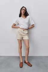Short de tiro medio color beige, con bolsillos laterales y dobladillo en las piernas.