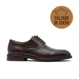 Zapato de vestir tipo derby, confeccionado en cuero vacuno de color marrón oscuro con acabado brillante. Presenta cordones al tono y suela de bloque bajo.