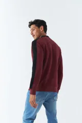 Buzo color bordó con cuello redondo y mangas largas con detalle de franja negra en los hombros. Tiene puños y logo "Mistral" estampado en relieve en el pecho.