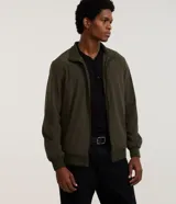 Campera bomber de color verde militar, con cuello alto, cierre frontal por cremallera y elástico en los puños y la cintura. Confeccionada por Marfinno.