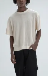 Remera de tejido de punto color beige con moldería ligeramente oversize, cuello redondo y mangas cortas. Confeccionada en una mezcla de viscosa y poliéster que ofrece una caída fluida y textura suave.