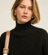 Suéter de manga larga confeccionado en tricot, con cuello alto y diseño de bordado de rombos en relieve. Presenta puños y ruedo acanalados.