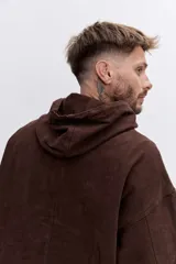 Campera tipo canguro color marrón, con capucha, cierre frontal parcial y bolsillo tipo sobre en el frente. Presenta puños elásticos y cordones ajustables en la capucha.