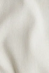 Musculosa color crema de punto acanalado, corte entallado, cuello redondo y ribete fino en escote y sisas.