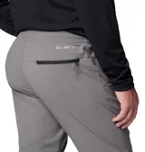 Pantalón técnico Columbia de corte ajustado en color gris, con cintura elástica ajustable mediante cordón y puños elásticos en los tobillos. Presenta paneles reforzados en la parte superior y bolsillos laterales y traseros con cierre.