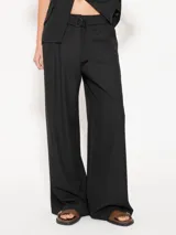 Pantalón negro de lanita viscosa, corte wide leg con gran caída y movimiento. Acceso mediante cierre metálico, gancho pantalonero y botón interno. Incluye lazo en cintura con media caña marcaria de níquel.