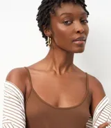 Blusa básica negra de breteles finos, confeccionada en malla de algodón peruano con escote redondo.