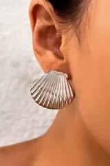 Par de aros plateados con forma de concha marina con textura acanalada.