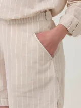 Short de tiro alto confeccionado en mezcla de lino y algodón orgánico, con diseño de rayas verticales en tonos beige y blanco. Presenta bolsillos laterales y cierre invisible.