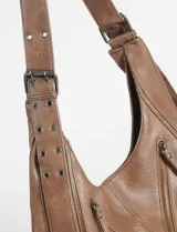 Cartera hobo negra de cuero sintético con costuras blancas decorativas y múltiples cierres diagonales en el frente. Tiene una correa de hombro ajustable.