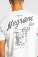 Camiseta blanca de manga corta con estampado gráfico en la espalda que ilustra un cóctel Negroni con texto descriptivo.