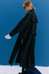 Trench midi color negro, confeccionado en mezcla de algodón y nylon con acabado repelente al agua. Presenta diseño con tajos laterales, bolsillos internos y etiqueta de marca en la espalda.