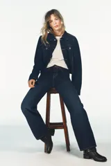 Jeans de tiro alto y pierna ancha con diseño de cinco bolsillos. Presenta una aplicación en la cintura de piel a contraste y cierre frontal con cremallera y botón metálico.