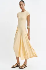Vestido largo color amarillo pastel, confeccionado con mezcla de viscosa, con cuello redondo, manga corta y bajo asimétrico fruncido con volumen.