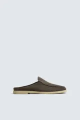 Mocasín destalonado de hombre, color marrón oscuro, con parte superior de serraje (gamuza) y horma redonda. Presenta una suela de contraste de color claro con un ligero tacón.