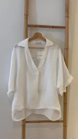 Blusa blanca de lino con cuello camisero, escote en V y mangas cortas amplias.