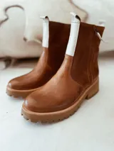 Botas de cuero color blanco con suela chunky y detalles en tono tostado, con cierre lateral y tirador en la parte trasera.