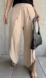 Pantalón color beige de corte palazzo con abertura lateral en la parte inferior de la pierna.