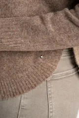 Sweater de tejido de punto con diseño de bloques de color en tonos beige, blanco roto y bordó. Presenta cuello redondo y mangas largas.