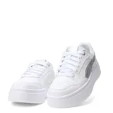 Championes Puma modelo Rebound Low con plataforma, color blanco con detalle de logo lateral en plateado metalizado. Diseño de caña baja con cordones y suela de goma gruesa.