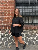 Camisa blanca de manga larga con detalles de encaje o bordado en el canesú y el frente. Presenta un corte holgado y mangas con puños elásticos o fruncidos.