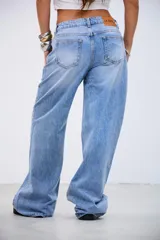 Jean de tiro medio en color celeste, con corte recto y holgado. Presenta detalle de tachas metálicas pequeñas a lo largo de las costuras laterales y en la zona de los bolsillos delanteros.