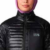 Campera acolchada de mujer Mountain Hardwear, color negro, con cierre frontal, cuello alto, bolsillo en el pecho y puños elásticos con detalle en color lila.