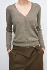 Chaqueta tipo cárdigan de lana, color beige, con escote en pico, manga larga y cierre frontal con botones.