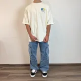 Pantalón de jean estilo cargo con corte baggy, color azul lavado. Presenta cuatro bolsillos laterales de gran tamaño con solapa y cierre de botones, diseño de pierna ancha y tiro medio.