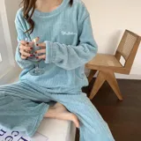 Conjunto de pijama de dos piezas confeccionado en tela de plush texturizada con diseño de rayas verticales en relieve. Incluye una remera de manga larga con cuello redondo y un pantalón de corte holgado. La remera presenta un pequeño bordado decorativo en el pecho.