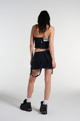 Top tipo corset de denim negro, sin mangas, con botón decorativo y cierre en la espalda.