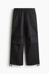 Pantalón cargo negro de algodón con corte holgado, cintura elástica con cordón de ajuste, múltiples bolsillos con solapa en las piernas y cordón ajustable en los bajos.