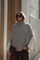 Poncho tejido de punto en color gris, con cuello alto y diseño holgado de estilo capa.