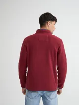 Buzo de polar color borgoña y marrón, con cuello alto con botones a presión y bolsillos laterales.