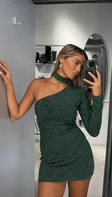 Vestido corto de fiesta color verde esmeralda con acabado brillante y textura sutil. Presenta un diseño asimétrico de un solo hombro con manga larga y detalle de cuello tipo choker integrado.