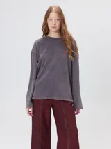 Remera oversize de manga larga color naranja con efecto gastado, cuello redondo y gráfico estampado en la espalda.
