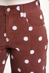 Jean de tiro alto color marrón rojizo con estampado de lunares blancos, corte recto y costuras decorativas frontales.