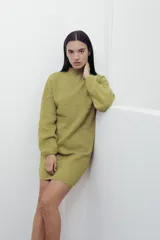 Vestido corto de punto color fucsia, con cuello alto y mangas largas amplias. Diseño holgado y cómodo.