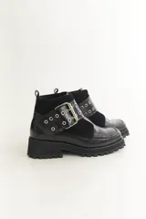 Botas cortas negras de cuero con punta cuadrada, hebilla plateada, ojales metálicos y suela track.