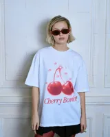 Remera blanca de algodón con cuello redondo y mangas cortas. Estampado frontal de dos cerezas rojas con la frase "Cherry Bomb!".