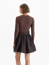 Remera de manga larga color marrón, confeccionada en tejido de punto suave y elástico. Presenta escote redondo a la base y una estampa frontal con diseño de cerezas.