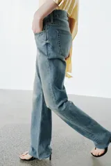 Jeans de tiro medio con corte slim y largo completo. Presentan diseño de cinco bolsillos, cierre frontal con cremallera y botón, efecto lavado y detalle de rotura en la parte delantera con bajo sin costura.