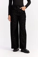 Jean de corte wide leg y tiro medio, confeccionado en algodón con estampado animal print en tonos negros. Presenta un diseño de pierna amplia y cierre frontal con botón y cremallera.
