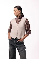 Chaleco tejido de punto con escote en V y cierre frontal con botones. Presenta una silueta recta y un diseño minimalista.