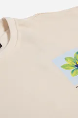 Buzo de felpa color beige de manga corta, con escote redondo y estampado de una flor amarilla y azul en el frente.