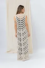 Chaleco largo tejido en punto calado color beige, de silueta recta y caída fluida. Presenta un diseño artesanal con transparencias sutiles que aportan textura y movimiento.