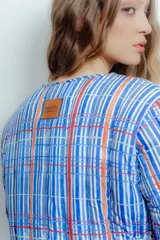 Campera corta de nylon impermeable con estampado a cuadros en tonos azul, blanco y naranja.