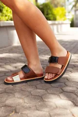 Sandalias de cuero color marrón con dos tiras ajustables, una de cuero liso y otra con textura de cocodrilo en color negro.