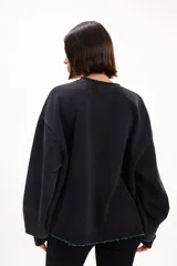 Buzo oversize color marrón con cuello redondo, mangas largas amplias y puños acanalados. Presenta letras en relieve con efecto desflecado en el frente y ruedo con terminación desflecada.